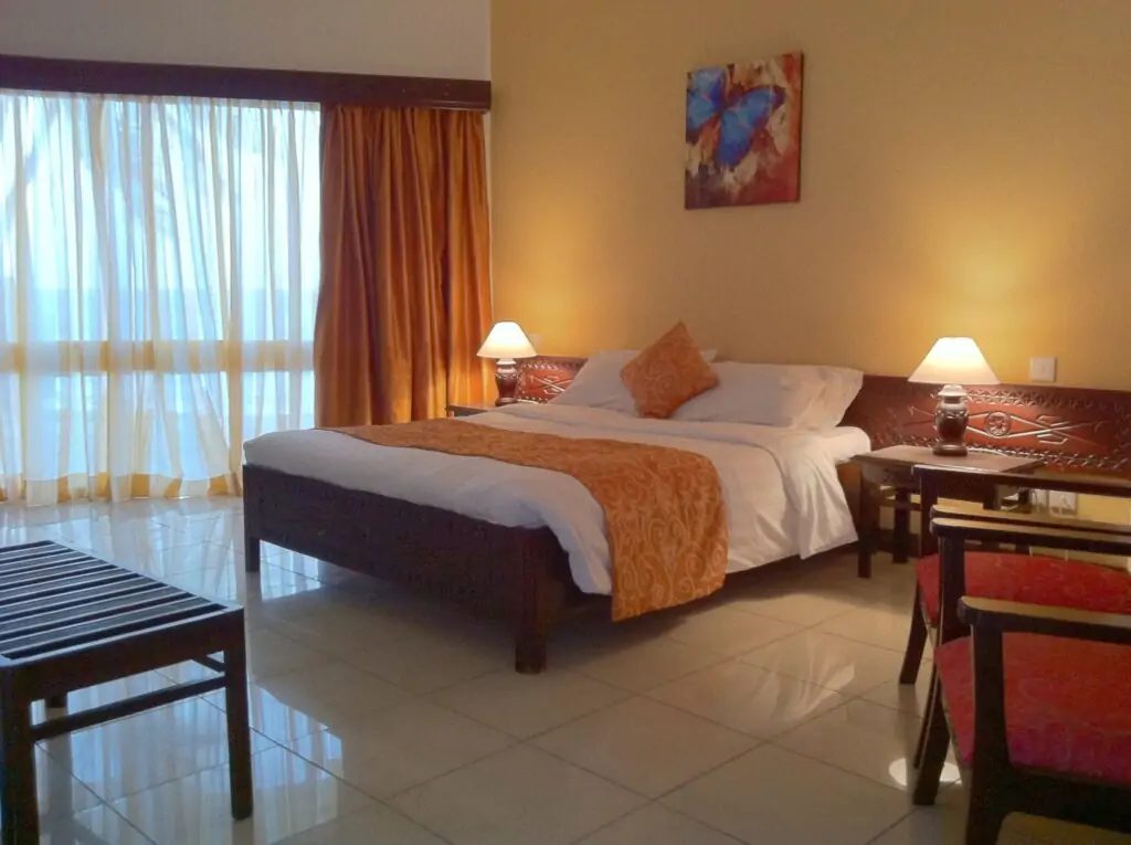Deluxe double room with king bed and balcony doors — Kenya Bay Beach Hotel, Bamburi Beach Mombasa